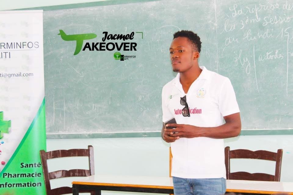 Jeph Jacquet présentant devant une salle, banderole Jacmel Takeover