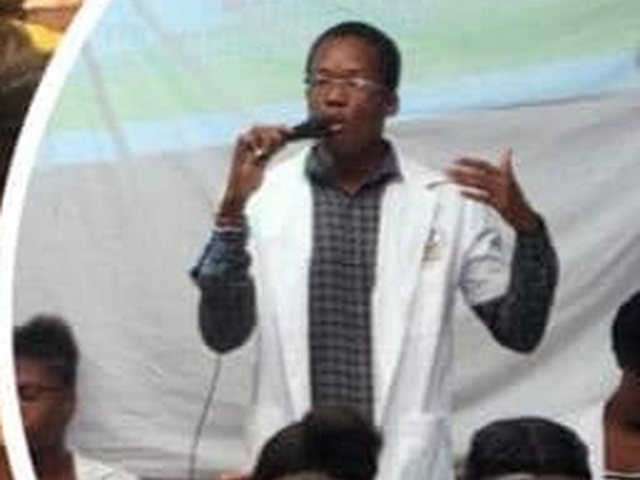 Jeph Jacquet au micro devant une salle, sous la bannière PHARMINFOS Haïti